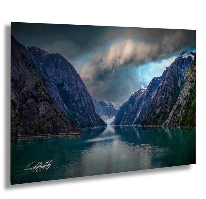 a serene landscape with a large body of water surrounded by towering mountains under a dramatic cloudy sky.