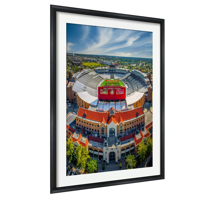 An aerial view of a large stadium with a red roof and a large sign on top.