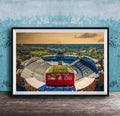 The image is a framed photograph of a football stadium, specifically the dome stadium at Duke Campbell Stadium, with a cityscape in the background.