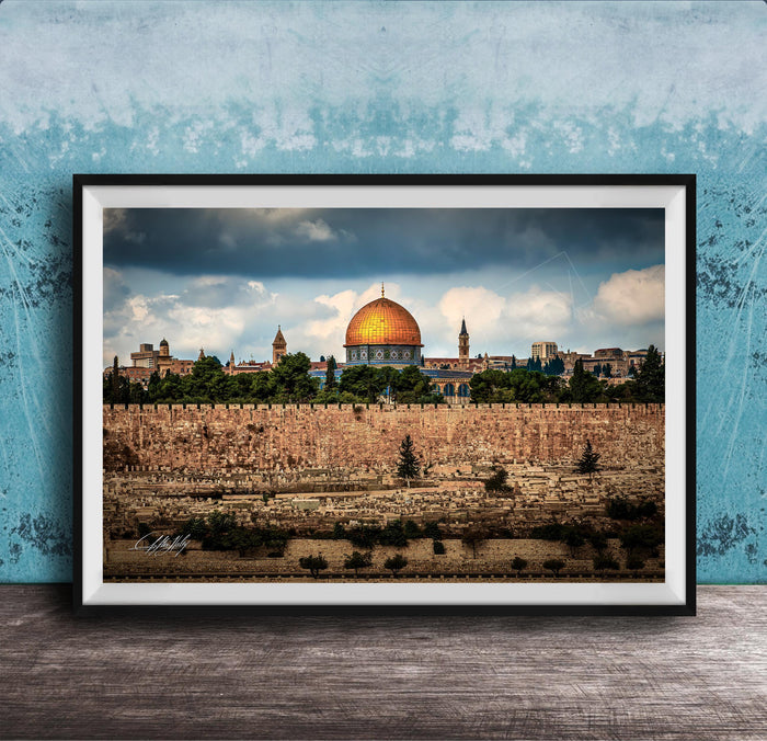 the Dome of the Rock, a significant landmark in Jerusalem, Israel. The photograph is framed and displayed on a wooden surface, showcasing the architectural beauty of the structure against a cloudy sky.