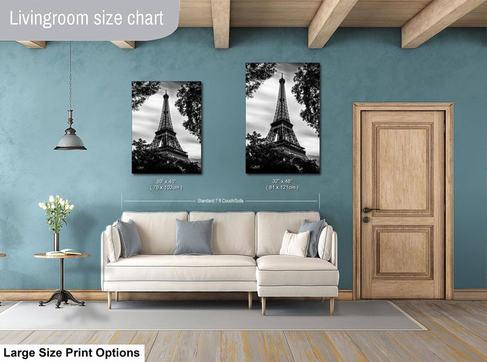 a living room with a white sofa, a wooden door, and two framed pictures of the Eiffel Tower hanging on the wall.