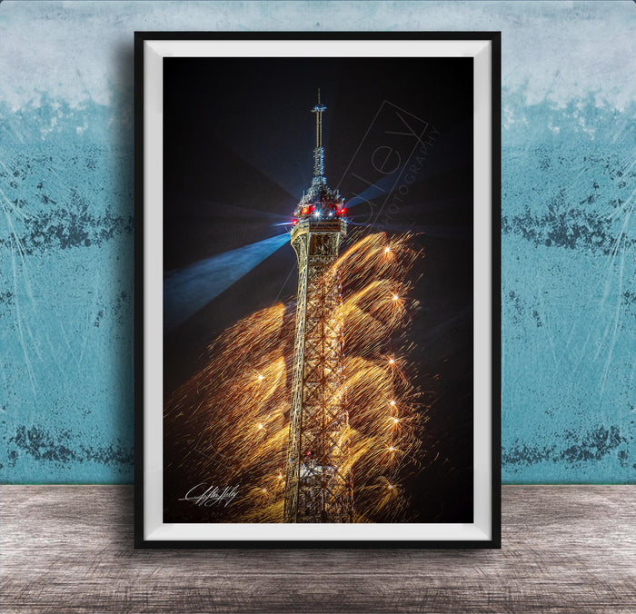A framed photograph of the Eiffel Tower with a fireworks display in the background, creating a vibrant and colorful scene.