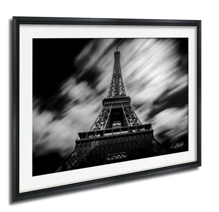 A black and white photograph of the Eiffel Tower in Paris, France, with a blurred background and a sense of motion.