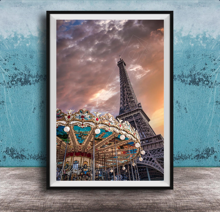 A framed photograph of the Eiffel Tower and a colorful carousel, set against a dramatic sky with clouds.