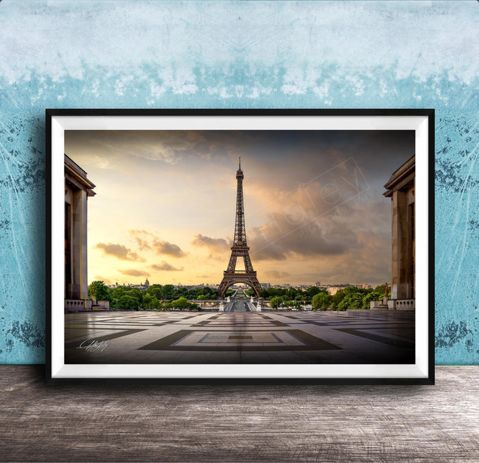 a framed photograph of the Eiffel Tower in Paris, France, with a dramatic sky in the background.