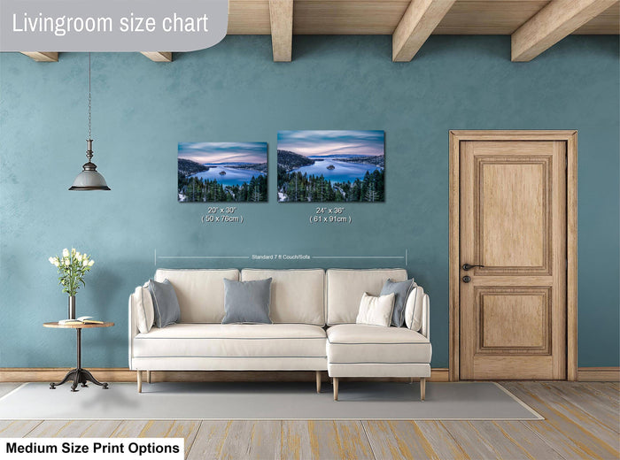 a living room with a white sofa, a wooden door, and a painting of a landscape on the wall. The painting is of a lake surrounded by trees, and it is of medium size. The living room has a blue wall and a wooden floor.