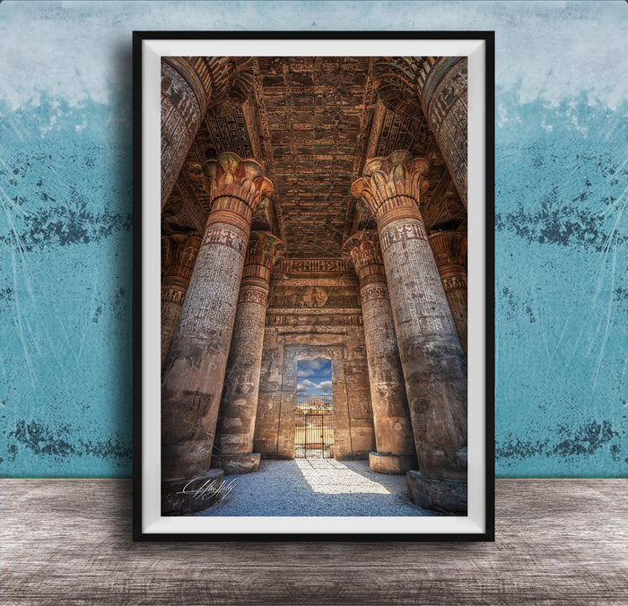 an ancient Egyptian temple with towering columns and intricate carvings, set against a blue wall with a textured pattern.
