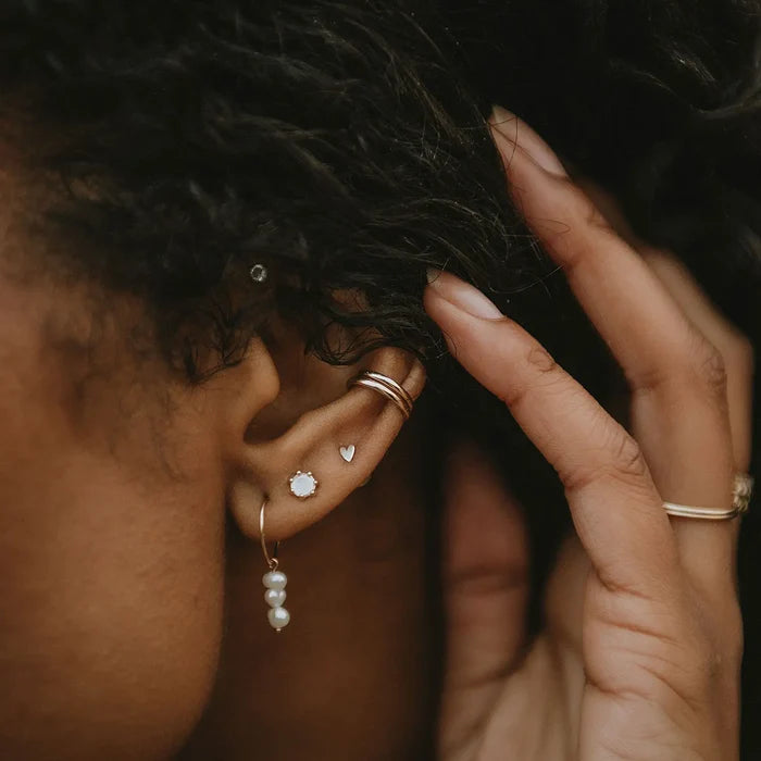 Everyday Little Lovely Heart Earring in 14k yellow gold, shown worn on hand