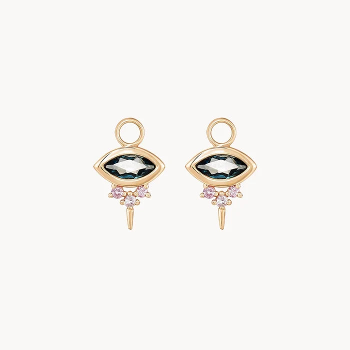 Front view of a pair of evil eye shaped earring charms with marquise-shaped london blue topaz at the centre and three small pink sapphires underneath followed by a small spike at the bottom displayed on a clean off-white background.