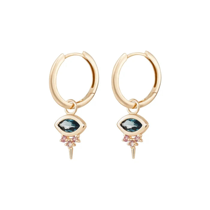 Side view of a pair of evil eye shaped earring charms with marquise-shaped london blue topaz at the centre and three small pink sapphires underneath followed by a small spike at the bottom, hung on gold hoop earrings and displayed on a clean off-white background.