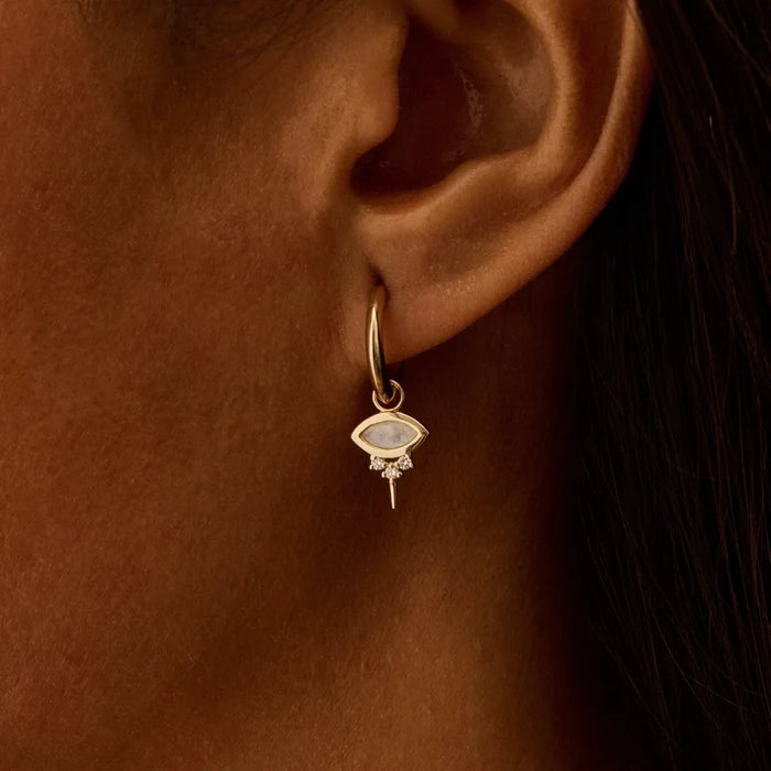 a woman wearing a solid gold hoop with an evil eye earring charm with natural moonstone and diamonds