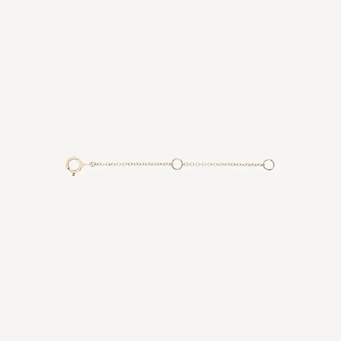 The Extender - 14k yellow gold by bluboho is a delicate accessory that features a clasp at one end and a loop at the other. It includes a small chain with two additional loops evenly spaced along its length. The extender is showcased against a plain white background.
