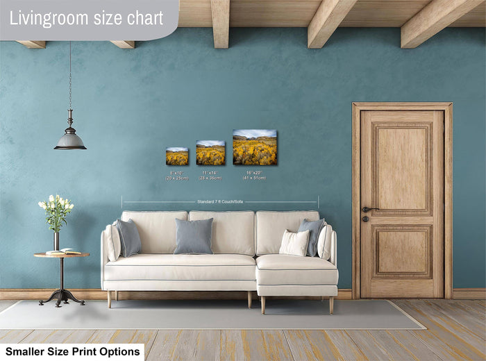 a living room with a white sofa, a wooden door, and a painting of a field of flowers on the wall.
