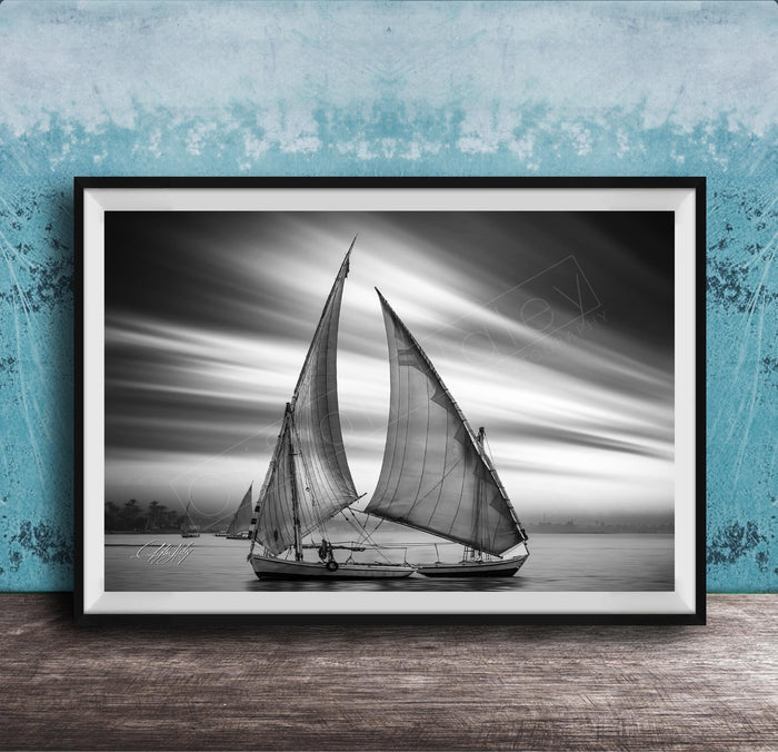 This luxury black and white fine art photograph captures a felucca sail boat drifting along the Nile River at sunset near Luxor, Egypt. Soft fog and minimalist composition create a timeless, monochrome aesthetic rooted in Egyptian river culture. Ideal for collectors and interior designers seeking refined, museum-quality wall art that embodies elegance, simplicity, and enduring calm. black white nile river art, felucca sailboat wall decor, luxor egypt monochrome print, luxury minimalist wall art