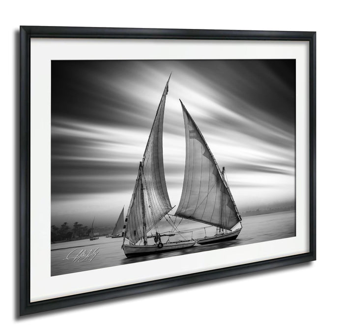This luxury black and white fine art photograph captures a felucca sail boat drifting along the Nile River at sunset near Luxor, Egypt. Soft fog and minimalist composition create a timeless, monochrome aesthetic rooted in Egyptian river culture. Ideal for collectors and interior designers seeking refined, museum-quality wall art that embodies elegance, simplicity, and enduring calm. black white nile river art, felucca sailboat wall decor, luxor egypt monochrome print, luxury minimalist wall art