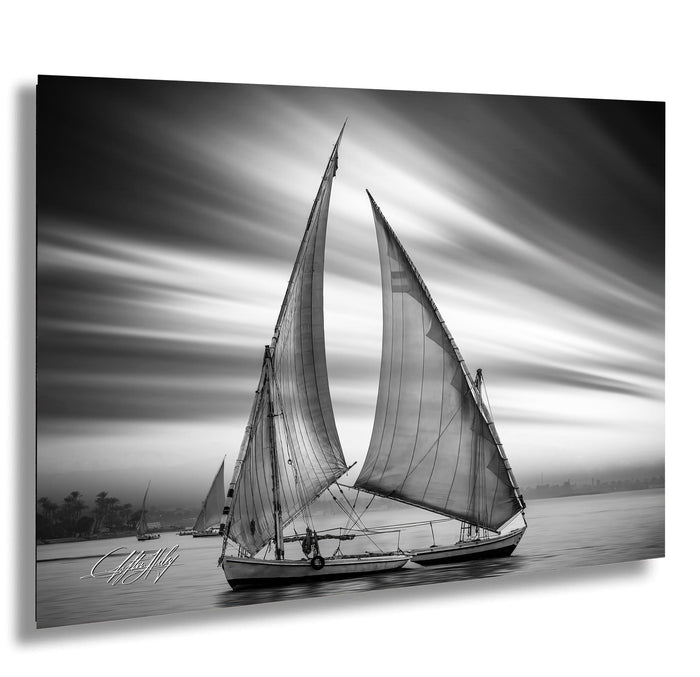 This luxury black and white fine art photograph captures a felucca sail boat drifting along the Nile River at sunset near Luxor, Egypt. Soft fog and minimalist composition create a timeless, monochrome aesthetic rooted in Egyptian river culture. Ideal for collectors and interior designers seeking refined, museum-quality wall art that embodies elegance, simplicity, and enduring calm. black white nile river art, felucca sailboat wall decor, luxor egypt monochrome print, luxury minimalist wall art