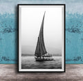 This luxury black and white fine art photograph captures a felucca sail boat drifting along the Nile River at sunset near Luxor, Egypt. Soft fog and minimalist composition create a timeless, monochrome aesthetic rooted in Egyptian river culture. Ideal for collectors and interior designers seeking refined, museum-quality wall art that embodies elegance, simplicity, and enduring calm.