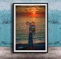 A framed photograph depicting a serene sunset over a body of water, with a pier extending into the water and a small building on the pier.