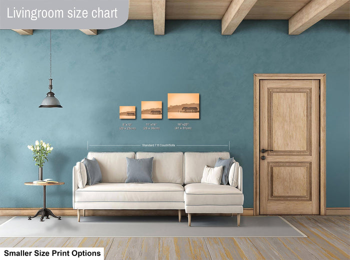 a living room with a white sofa, a wooden door, and a hanging light fixture. There are three framed pictures of different sizes displayed on the wall above the sofa.