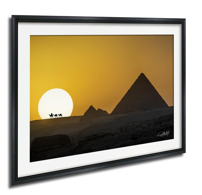 a desert landscape with a pyramid in the background and a camel caravan in the foreground, set against a vibrant yellow and orange sunset sky.