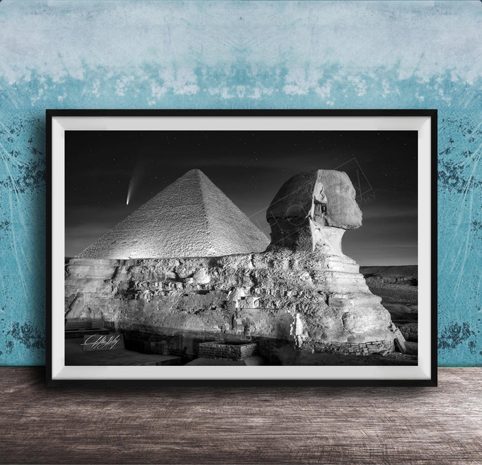 A black and white photograph of the Great Sphinx and the Pyramid of Giza against a night sky, with a small shooting star visible in the sky.