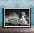 A black and white photograph of the Great Sphinx and the Pyramid of Giza against a night sky, with a small shooting star visible in the sky.