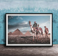 A framed photograph depicting a camel caravan in front of the iconic pyramids of Giza in Egypt.