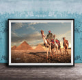 A framed photograph depicting a camel caravan in front of the iconic pyramids of Giza, Egypt, with a man riding one of the camels.