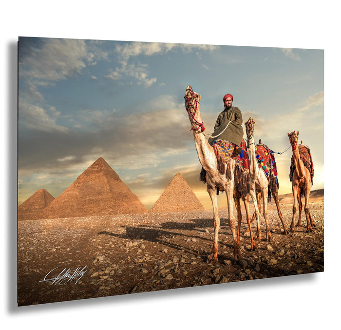 A man rides a camel in front of the iconic pyramids of Giza, Egypt, with a cloudy sky in the background.
