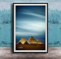 A framed photograph of the iconic pyramids of Giza in Egypt, with the sky and clouds in the background.