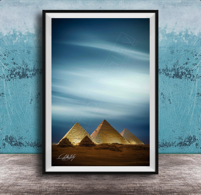 A framed photograph of the iconic pyramids of Giza in Egypt, with the sky and clouds in the background.