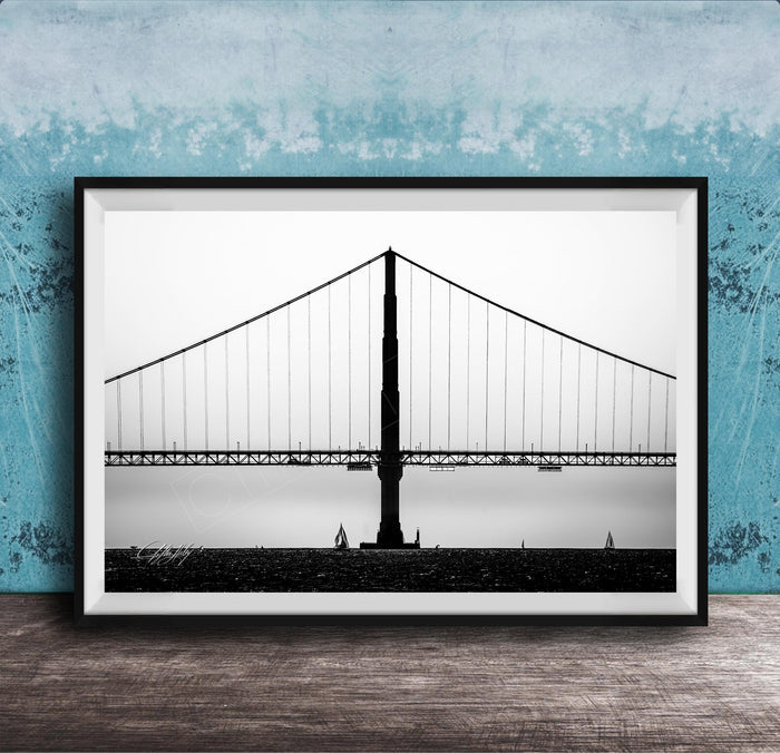 A black and white photograph of the Golden Gate Bridge in San Francisco, California, with a blue textured wall in the background.