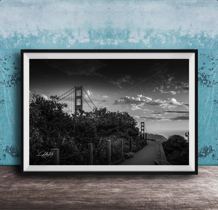 A black and white photograph of the Golden Gate Bridge in San Francisco, California, with a cloudy sky in the background.