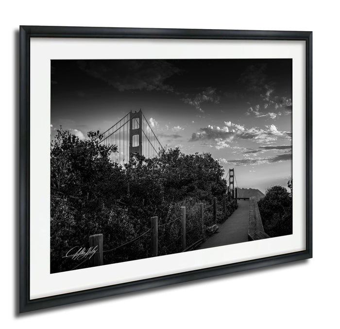 A black and white photograph of the Golden Gate Bridge in San Francisco, California, with a cloudy sky in the background.