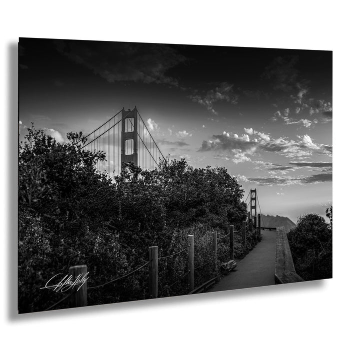A black and white photograph of the Golden Gate Bridge in San Francisco, California, with a cloudy sky in the background.