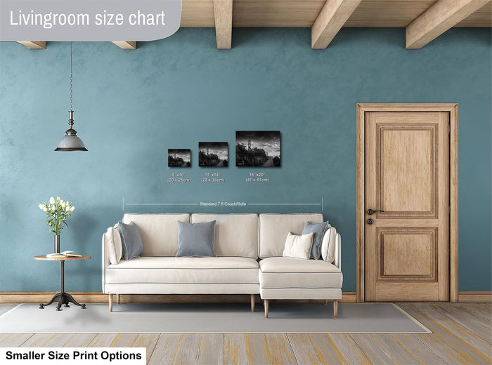 a living room with a white sofa, a wooden door, and a hanging light fixture. There are three framed black and white photographs hanging on the wall above the sofa.