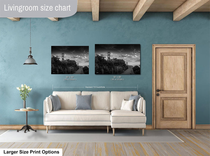 a living room with a white sofa, a wooden door, and two framed black and white photographs of the Golden Gate Bridge hanging on the wall.