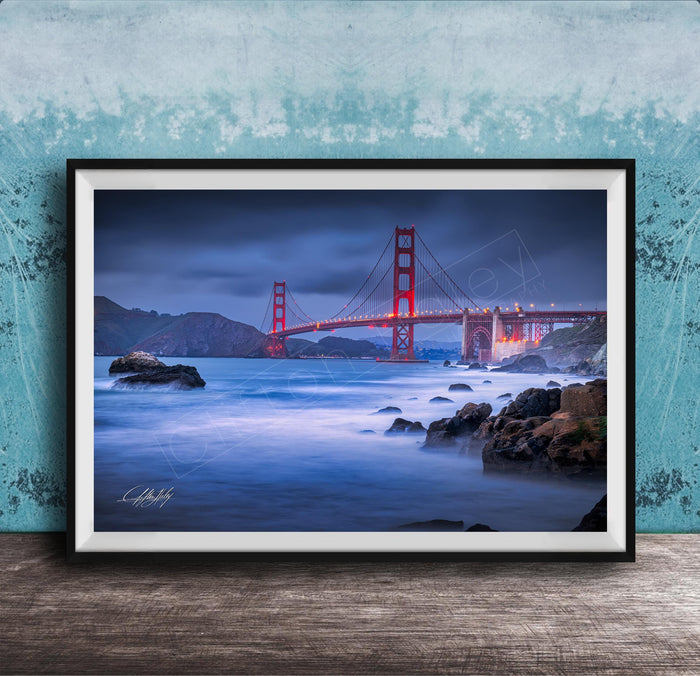 A framed photograph of the Golden Gate Bridge at night, with the bridge illuminated against a dark sky and the ocean in the foreground.