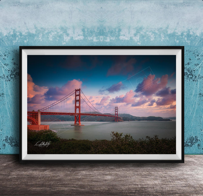 A framed photograph of the Golden Gate Bridge at sunset, with the bridge's distinctive red towers and suspension cables silhouetted against a colorful sky.