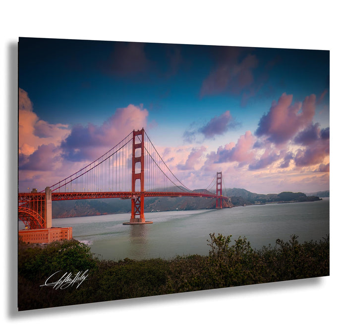 the Golden Gate Bridge, a famous suspension bridge in San Francisco, California, with its distinctive red towers and cables spanning the San Francisco Bay. The sky is filled with clouds, creating a dramatic backdrop for the iconic structure.