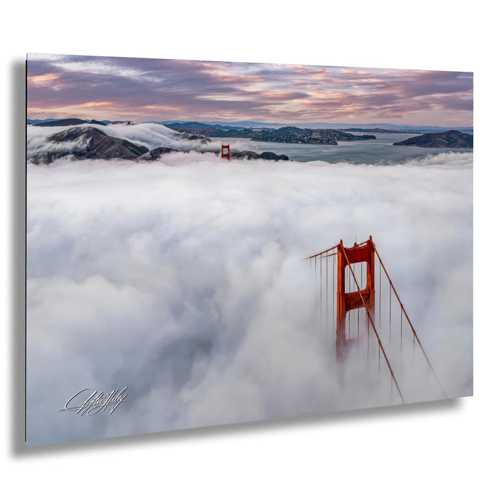 a suspension bridge with two towers, one of which is partially obscured by clouds, creating a dramatic and atmospheric scene.