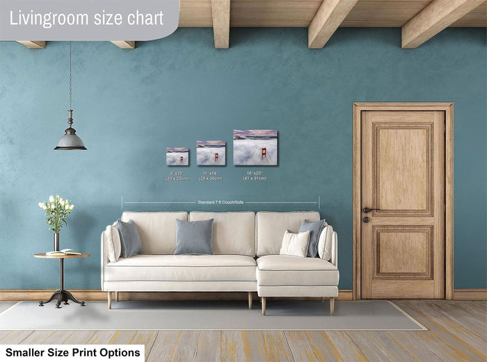 a living room with a white sofa, a wooden door, and a hanging light fixture. There are three framed artworks displayed on the wall, each with different sizes and dimensions. The living room appears to be well-decorated and spacious.
