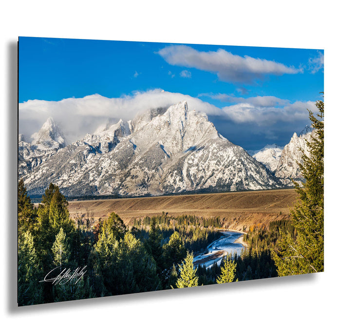 A breathtaking mountain landscape with snow-capped peaks, a winding river, and a lush forest in the foreground.