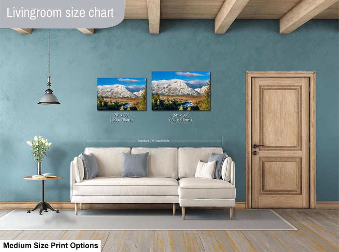 a living room with a white sofa and a wooden door. Above the sofa, there is a livingroom size chart that provides the dimensions of two framed landscape photographs hanging on the wall.
