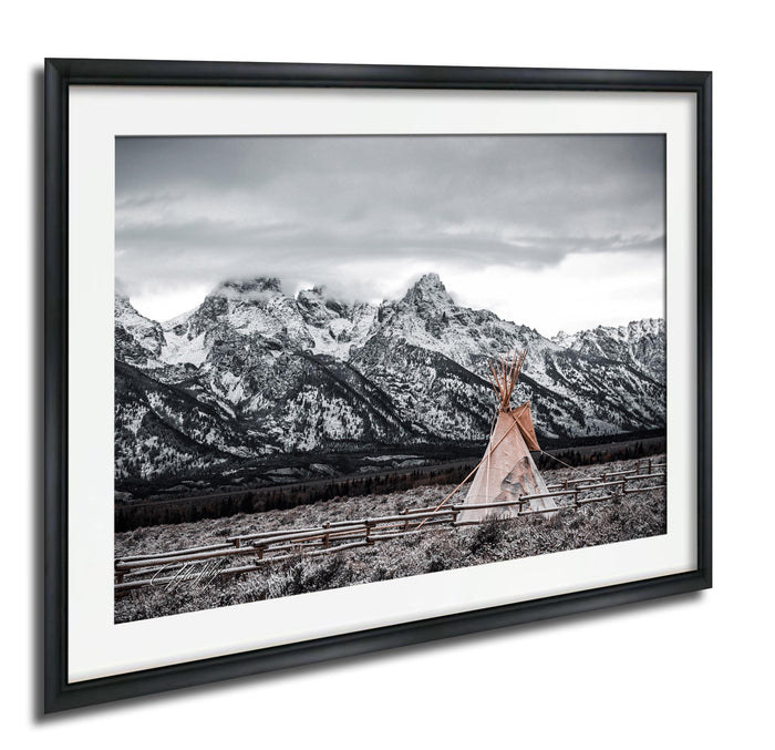 A framed photograph depicting a teepee in a snowy mountain landscape with a cloudy sky.
