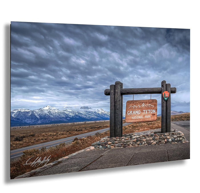 a scenic view of the Grand Teton National Park, with snow-capped mountains in the background and a cloudy sky above.