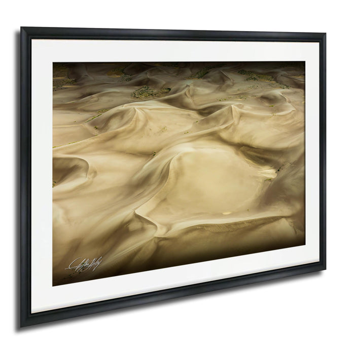 The image is a framed photograph of sand dunes, with a textured, wavy appearance.