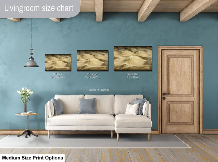 a living room with a white sofa, a wooden door, and a hanging light fixture. There are three framed artworks displayed on the wall, each with a different size and frame. The living room appears to be well-decorated and spacious.