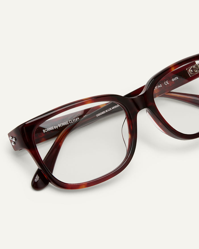 Close-up shot of Bonnie Clyde Guts optical frames in red tortoise with clear lenses.