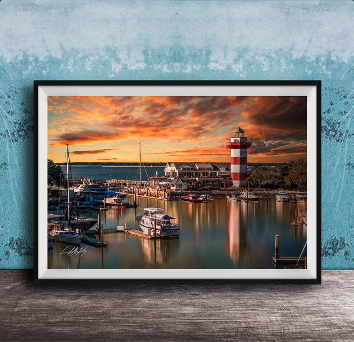 a serene harbor scene at sunset, with boats docked in the calm waters and a lighthouse standing tall in the background.